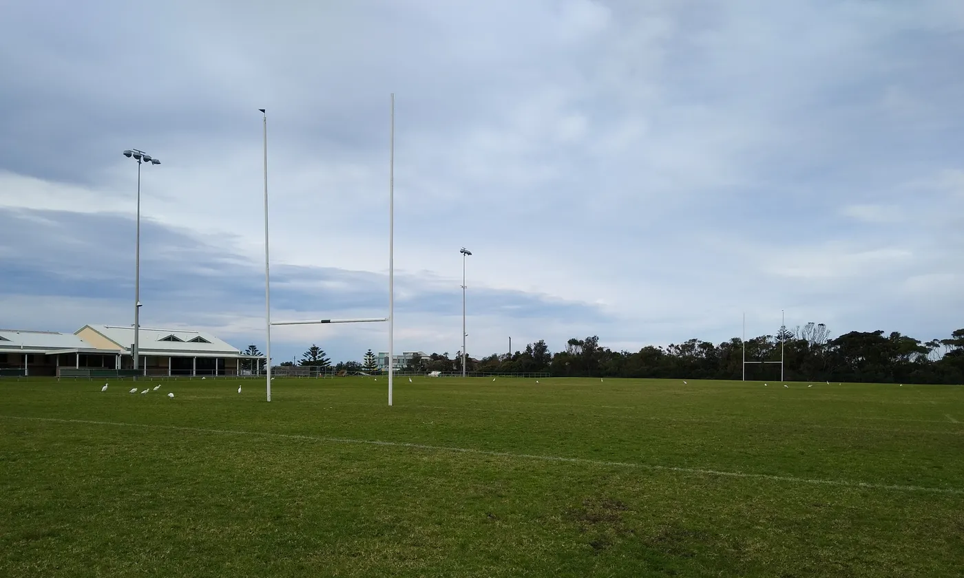Campo de hierba con postes de rugby en un día nublado, sin jugadores
