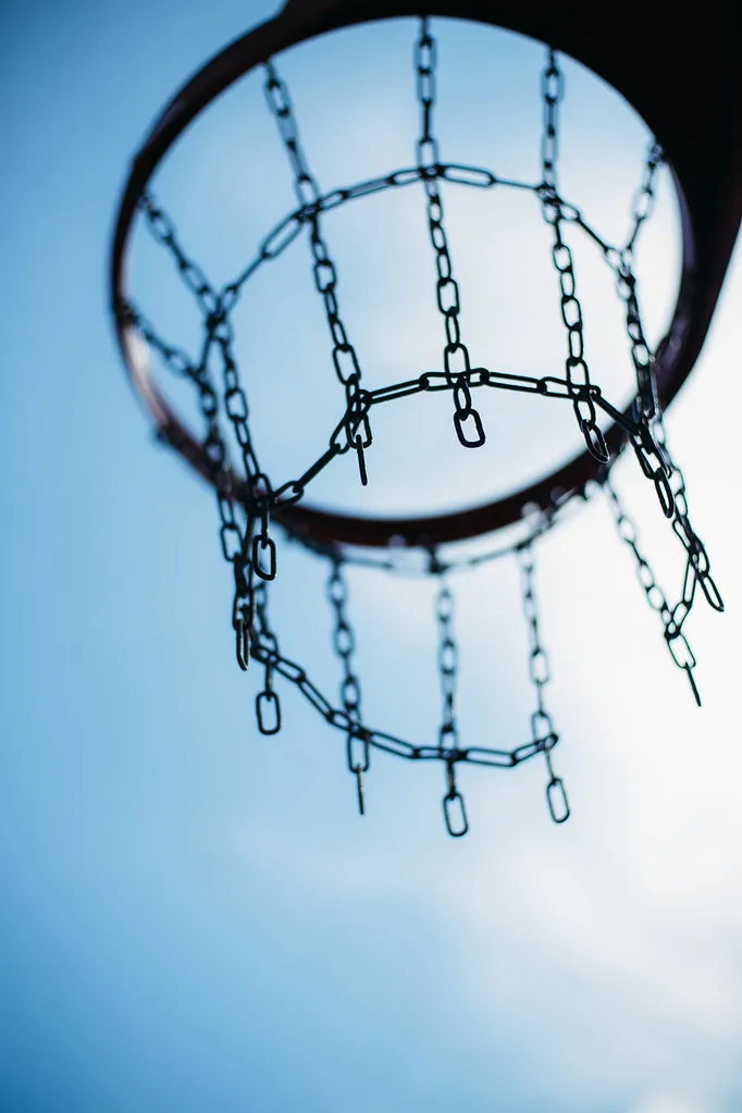 Aro de baloncesto con red de cadenas visto desde abajo contra el cielo