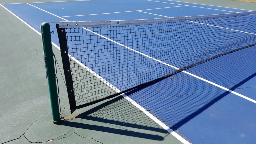 Red de tenis tensada sobre una pista de superficie dura azul con líneas blancas